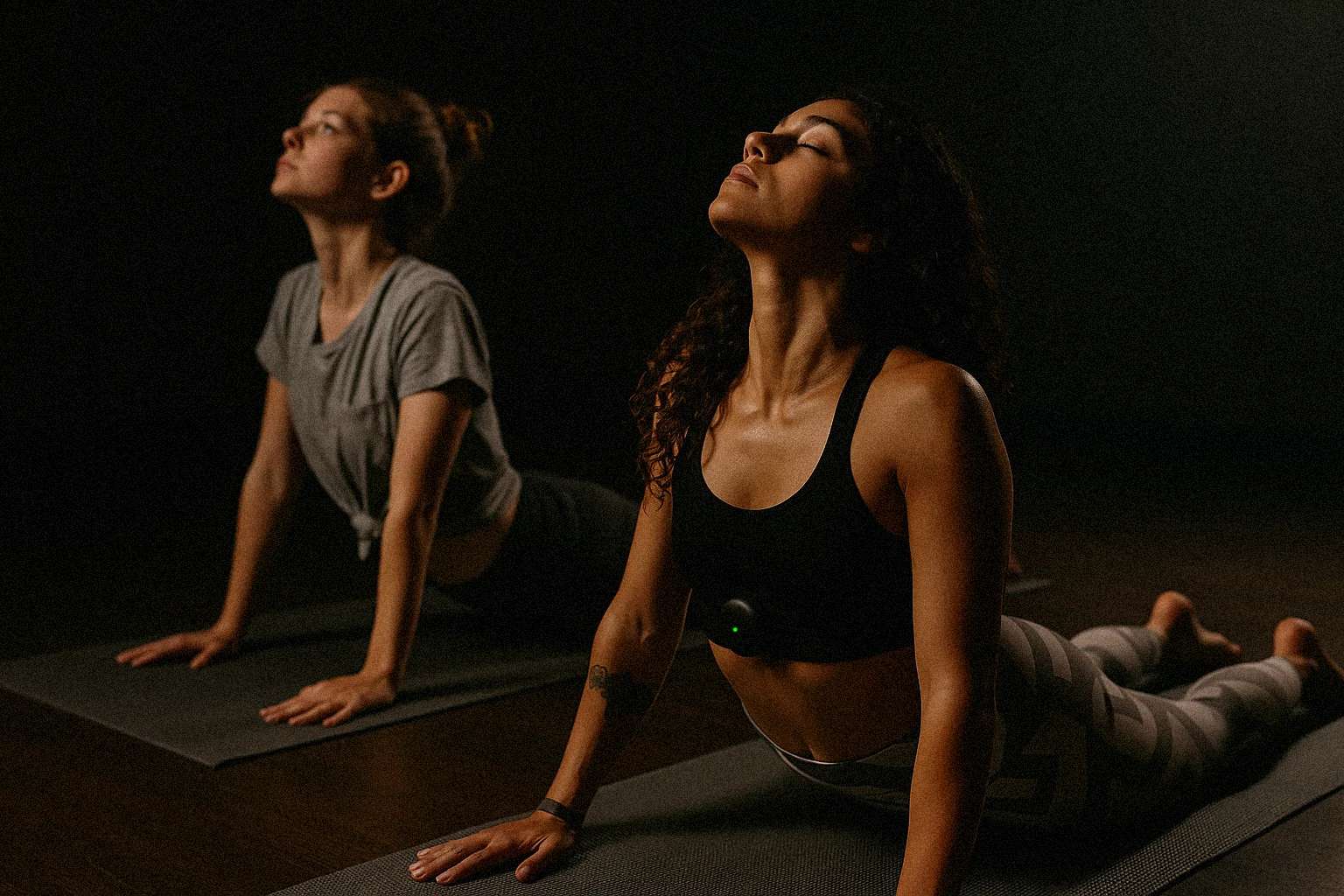 Two women practising yoga, one wearing Aidlab on a chest strap